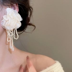 Detail of chiffon flower earrings with long pearl tassels on a model's ear