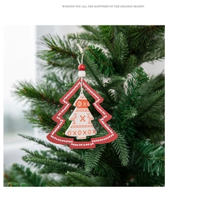 Detail of wooden Christmas tree ornament with reindeer patterns hanging on a green branch