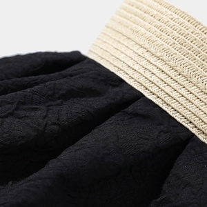 Dettaglio del tessuto stropicciato nero con fascia elastica in vita color beige