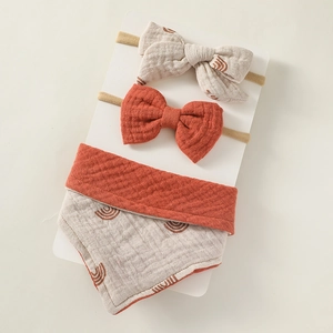 Detailed view of baby bib and bow headband set in soft waffle cotton with rainbow print