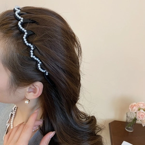 Detail of wave-shaped headband with pearls on black base worn by a female model