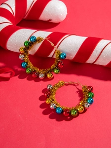 Detailed macro view of festive hoop earrings with colorful beads and tinsel on red background