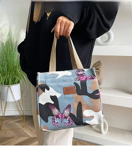 Détail du sac à lunch camouflage bleu avec motif papillon et étiquette en cuir