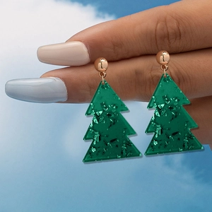 Gros plan de boucles d'oreilles sapin de Noël vert avec paillettes et tiges dorées