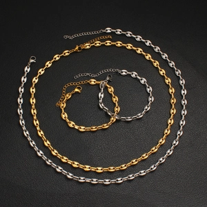 Set collana e bracciale a chicco di caffè in oro e argento su sfondo in pelle nera