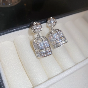 Macro shot of silver birdcage earrings with sparkling crystals and a central pearl detail