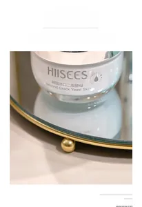 Detail view of skin cream on a mirror tray with elevated metal ball feet design
