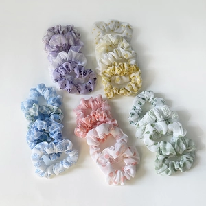 Set of colorful floral and plaid fabric scrunchies in pastel macaron tones on white background
