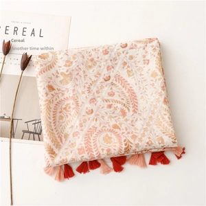 Detail view of cotton linen scarf with orange paisley prints and colorful fringe tassels