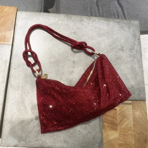 Detailed view of red rhinestone hobo bag with knotted handle and gold zipper closure