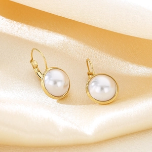 Close-up of elegant round shell earrings with gold plating on champagne satin fabric