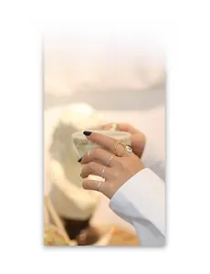 Detailed view of stacked minimalist gold and silver rings on hand holding a cup