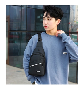 Close-up of black sling bag with white Fashion tag and zipper detail on modern male model