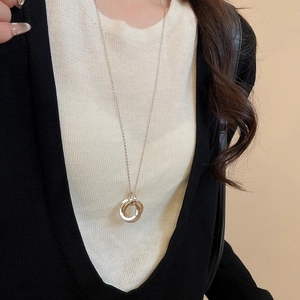 Detail of three-tone interlocking triple ring pendant necklace on black and white knitwear