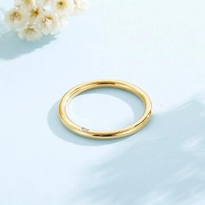 Detailed close-up of a minimalist gold ring featuring a sparkling single inset diamond