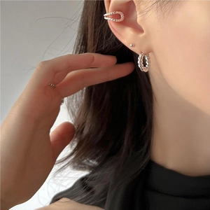 Detail of twisted rope silver earrings and ear cuff on model showing metal texture