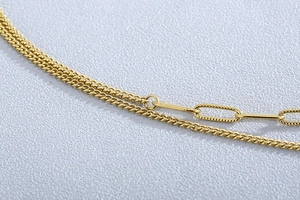 Détail macro du collier doré montrant la maille gourmette et les maillons rectangulaires