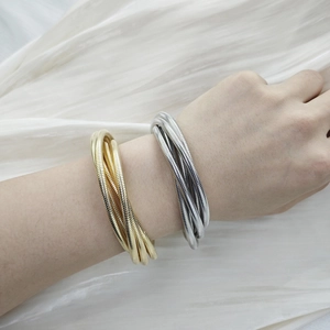 Close-up of layered gold and silver spring snake chain bracelets worn on a wrist