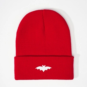 Detailed view of red ribbed knit beanie featuring a white embroidered bat logo