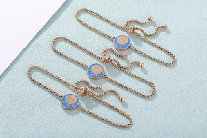 Dettaglio di bracciali zodiacali in oro rosa con smalto blu e chiusura a scorrimento regolabile