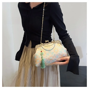 Detail of floral embroidery on a vintage clutch with metal clasp and green silk tassels