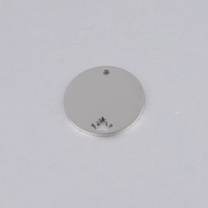 Macro detail of 20mm stainless steel round pendant with hollow crown pattern and hole