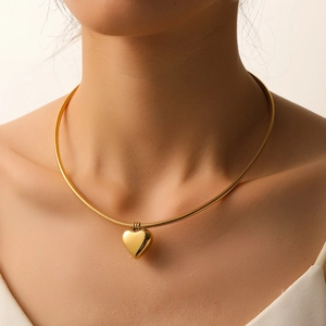 Close-up of golden heart pendant on a snake chain necklace worn by a model