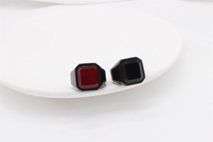 Close-up of men's square-cut gemstone rings in black and red on a white display