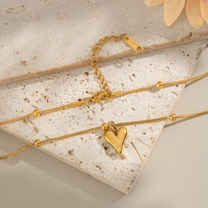Detailed view of golden stainless steel heart pendant on a snake bone chain texture