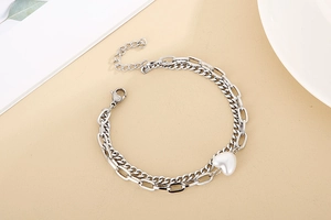 Detail of silver double-layer stainless steel bracelet featuring heart pendant and pearl charm