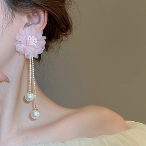 Macro detail of elegant pink lace flower earrings with dangling rhinestone pearls