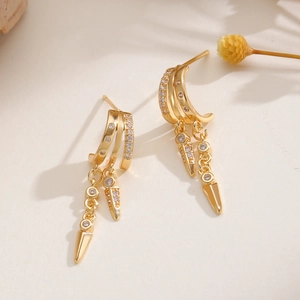 Close-up of golden tassel earrings with sparkling zircon inlay and cone pendants
