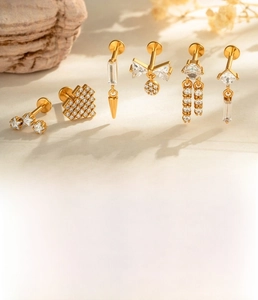 Detail of gold titanium steel labret studs with zircon heart and bow designs