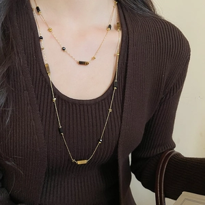Detail of tiger eye beaded necklace on model wearing dark brown knit sweater