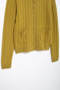 Macro detail of mustard yellow cable knit cardigan with texture and front pocket view
