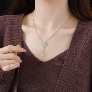 Detailed view of silver butterfly necklace with teardrop gemstone on a female model