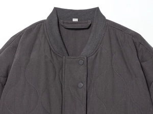 Detail view of dark grey quilted bomber jacket with ribbed collar and metal snap buttons
