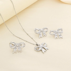 Silver bow jewelry set with necklace, ring and earrings on a minimalist background