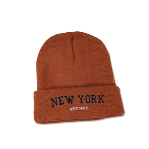Detail showing the New York embroidery on a brown knit beanie cap in high resolution
