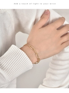 Nahaufnahme eines goldenen Büroklammer-Kettenarmbands mit Strass am Handgelenk