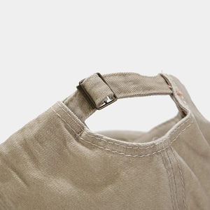 Detail of adjustable brass buckle and stitching on washed khaki cotton baseball cap
