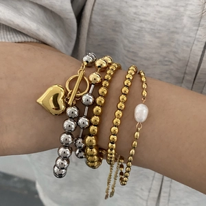 Close-up of five-piece mixed metal bead bracelet set with heart charm and pearl on wrist