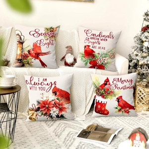 Close-up of four Christmas pillow covers with red cardinal prints on a cozy sofa
