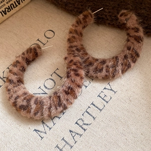 Detail view of large leopard print plush fabric hoop earrings with soft fuzzy texture
