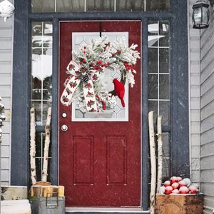 Christmas wreath featuring a red cardinal bird, snowy pine branches and red berries