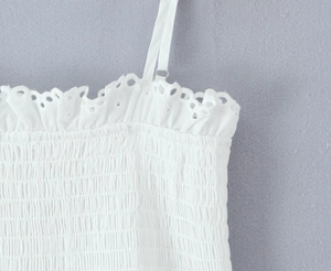 Vue détaillée du haut blanc en coton avec broderie délicate et texture plissée chic