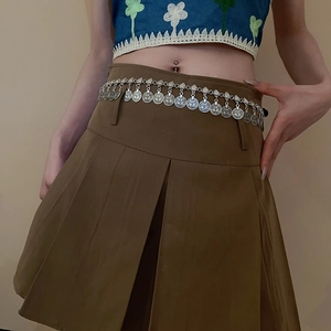 Detail view of silver coin tassel waist chain belt in bohemian style on a pleated skirt