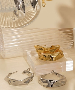 Detailed view of C-shaped irregular wavy earrings in gold and silver finish