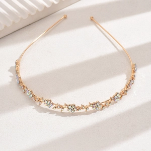 Close-up of golden floral headband with colorful rhinestones on a textured background