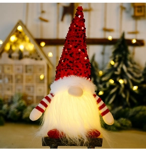 Close-up of glowing Christmas gnome with red sequins and warm interior LED lighting